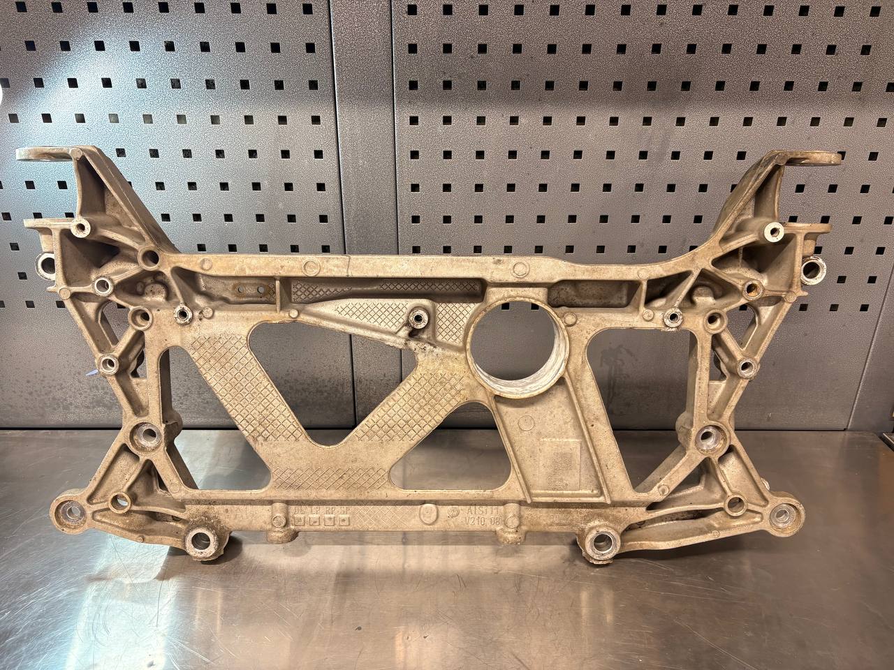 Used cast-aluminium automotive subframe with dull oxidation and grime before VMC vapour blasting